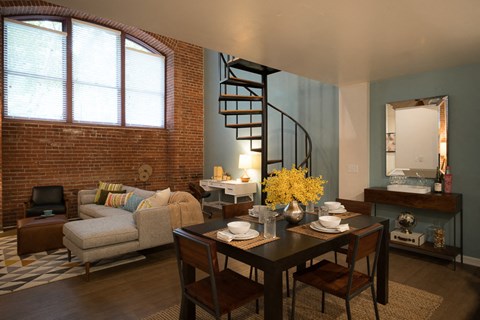 a living room with a dining room table and a spiral staircase