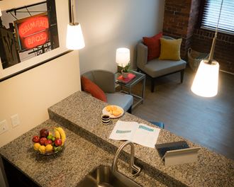 a kitchen counter with a bowl of fruit and a living room with couches