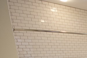bathroom with dark wooden cabinets, grey laminate floors and white tiled walls - Photo Gallery 4