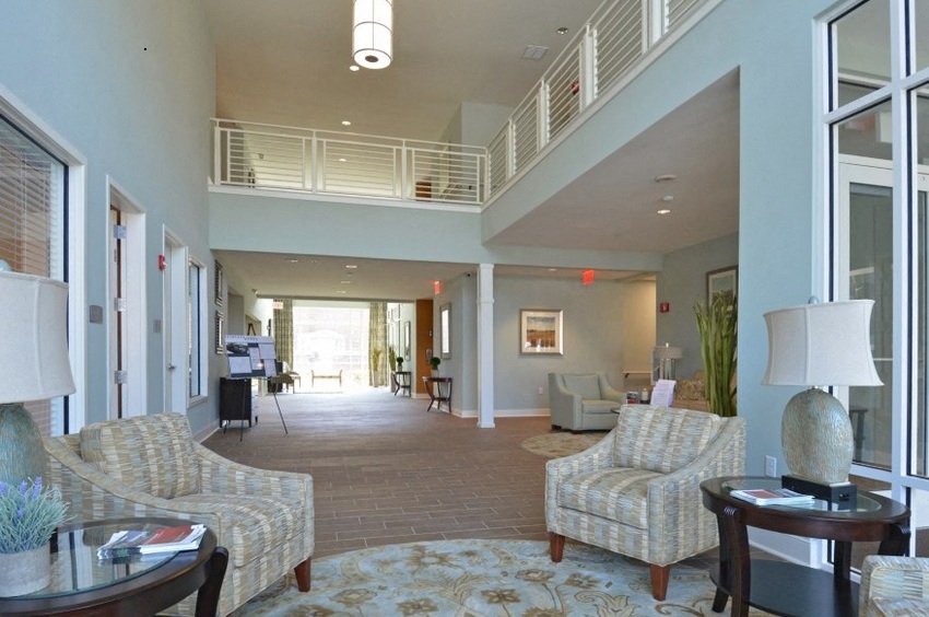 a living room with couches and chairs and a hallway with windows