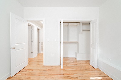an empty room with white doors and a wood floor