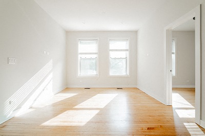a empty living room with two windows and a wood floor