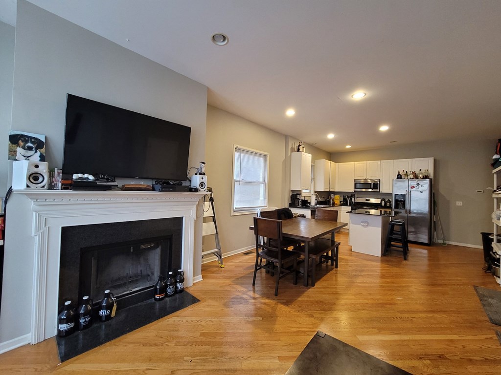 a living room with a fireplace and a kitchen with a table and chairs