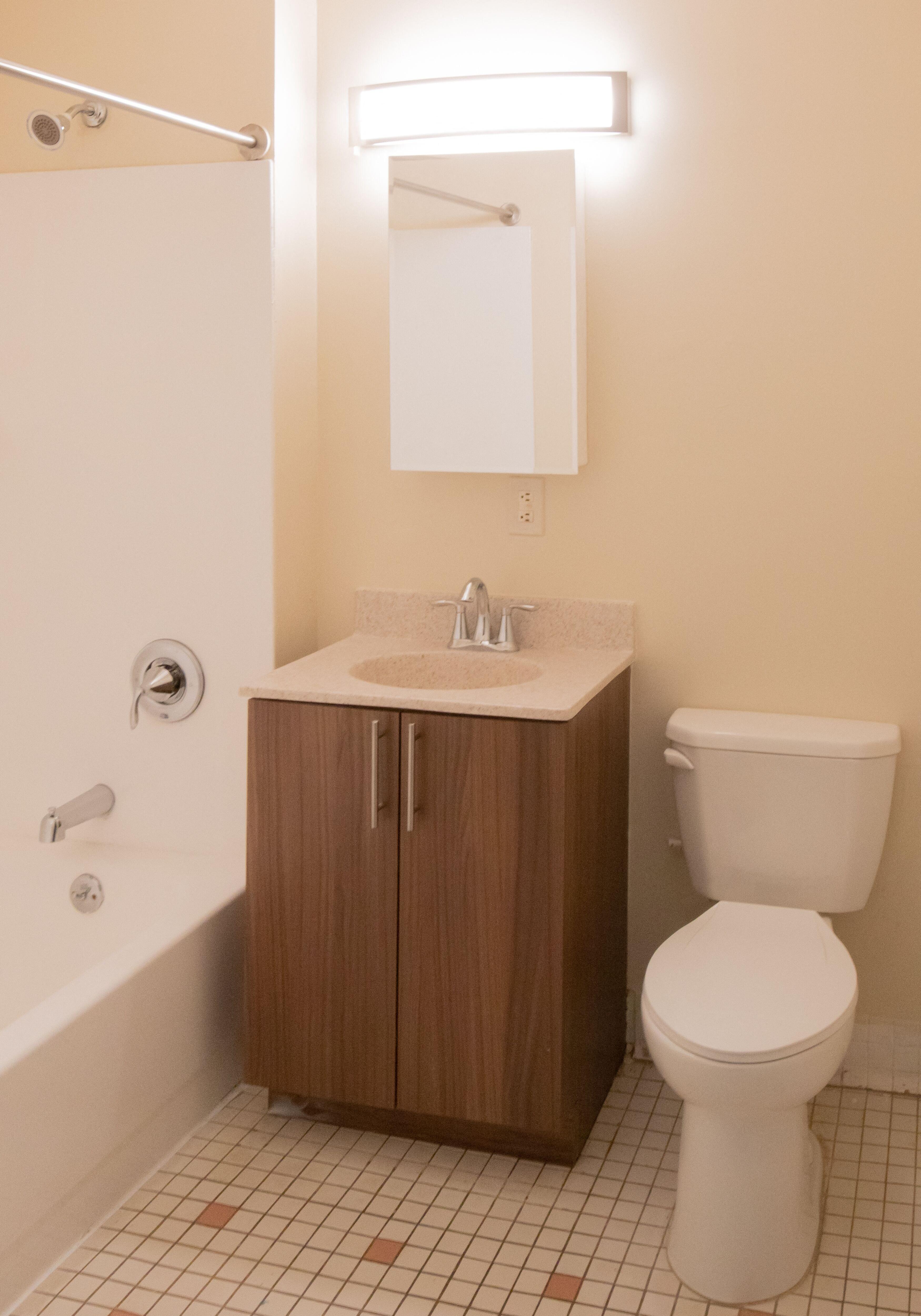 bathroom with wooden cabinet and white tile floors and off white walls