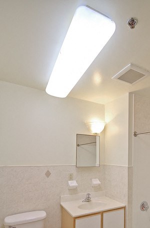 Bathroom with white walls, wooden & white cabinets, and white floors - Photo Gallery 5