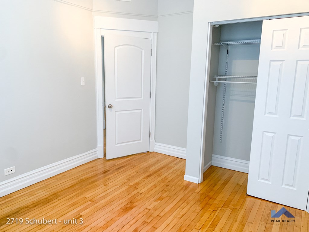 a bedroom with a wooden floor and a closet with a door