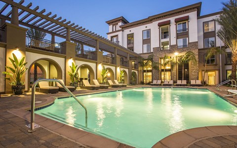 a swimming pool in front of a hotel at night