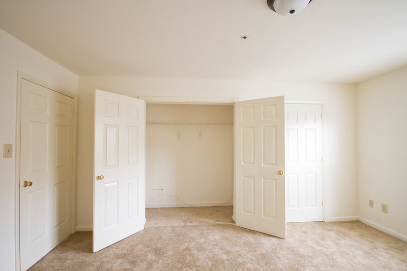 bedroom with white walls, carpeted floors and closets with double doors