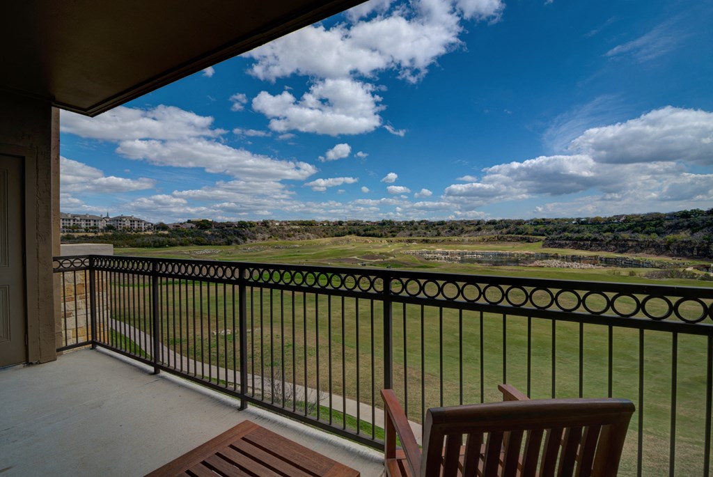 a balcony with a view of a field and a blue sky