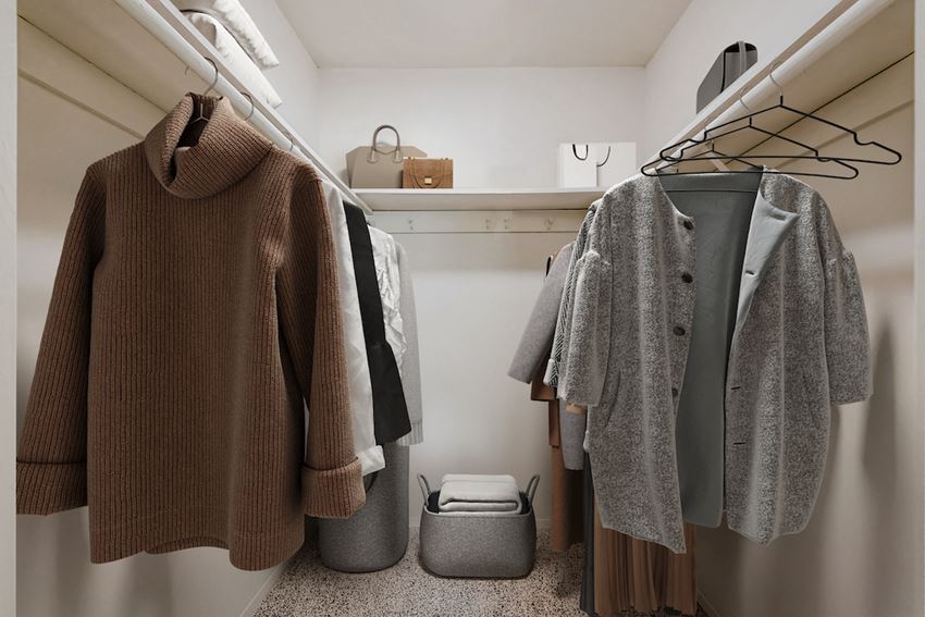 a walk in closet filled with sweaters and jackets