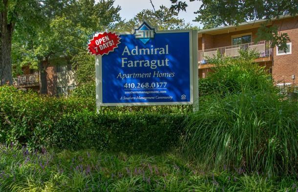 a sign is in the grass in front of an apartment building