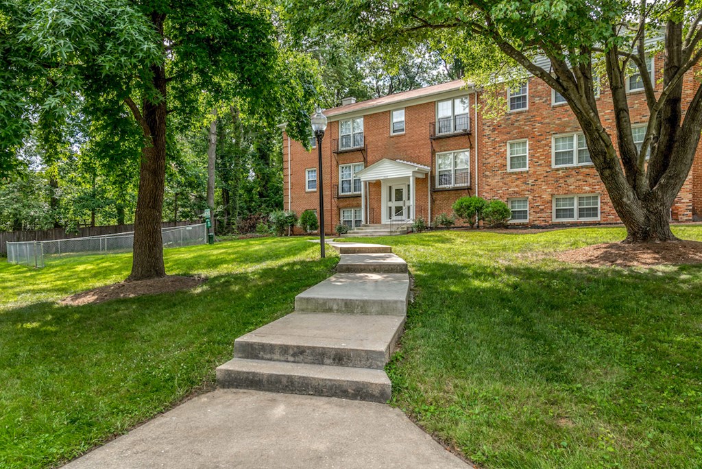 the sidewalk in front of a brick apartment building with trees