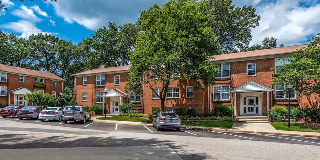 a large brick apartment building with cars parked in a parking lot