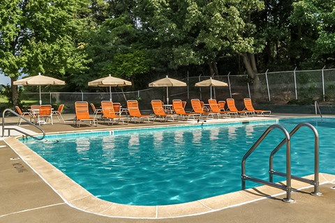 a swimming pool with orange chairs and umbrellas