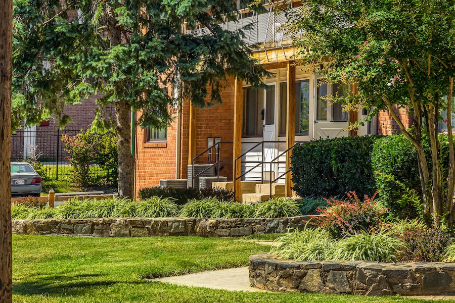the front porch of a brick house with trees and grass