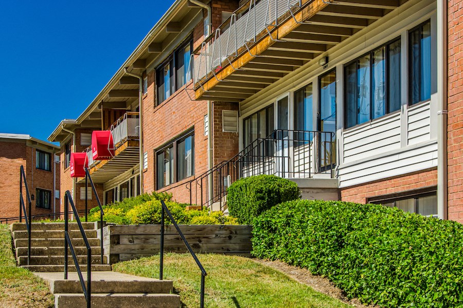 an exterior view of a brick apartment building with stairs and a green lawn