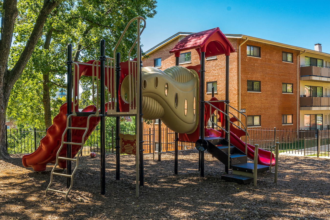 a playground with a slide and climbing equipment in front of a building