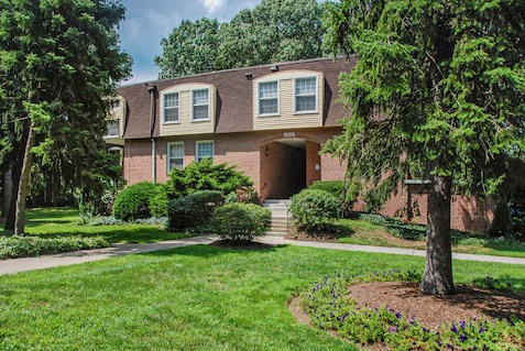 the front of a brick house with a lawn and trees