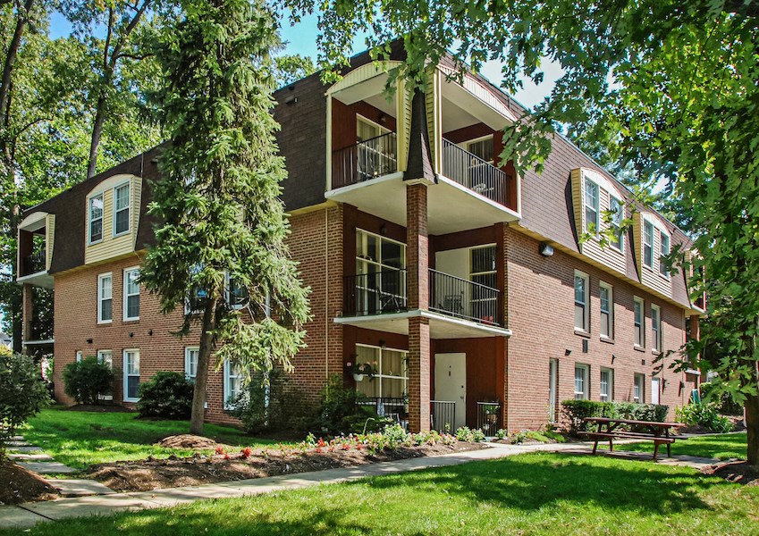 a brick apartment building with a lawn and trees
