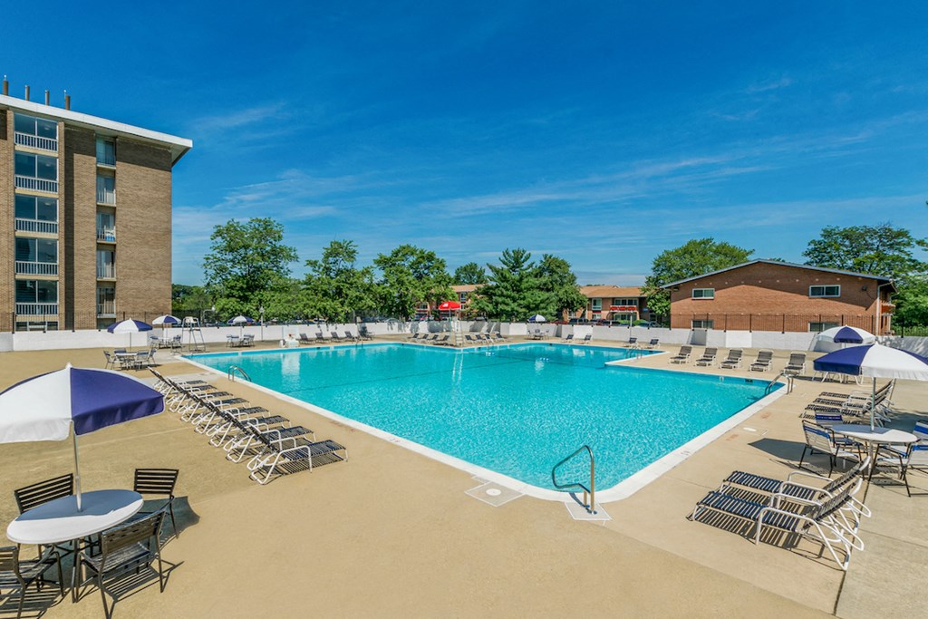 our resort style pool is surrounded by chairs and umbrellas