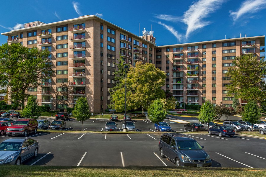 an empty parking lot with cars in front of a large building