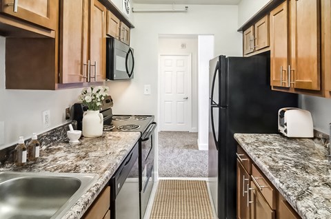 A kitchen with a black fridge and wooden cabinets.