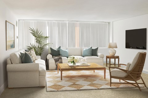 A living room with a white couch, a wooden coffee table, and a TV on the wall.