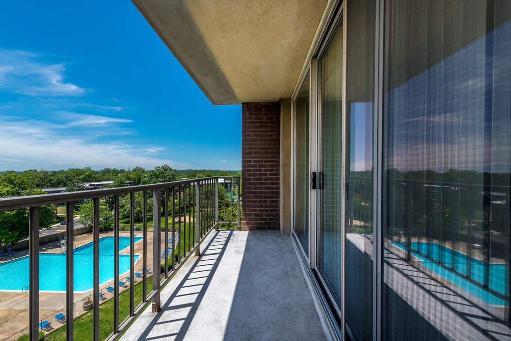 a balcony with a view of a swimming pool and a blue sky