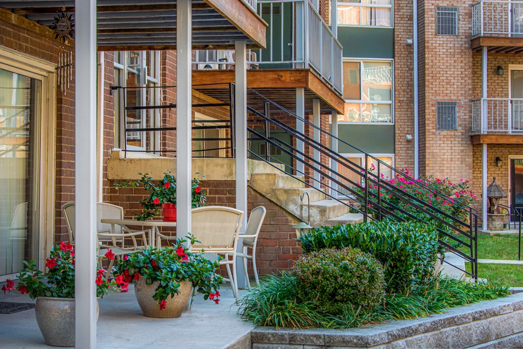a patio with chairs and flowers in front of a building