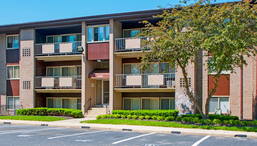 an apartment building with balconies and a tree in front