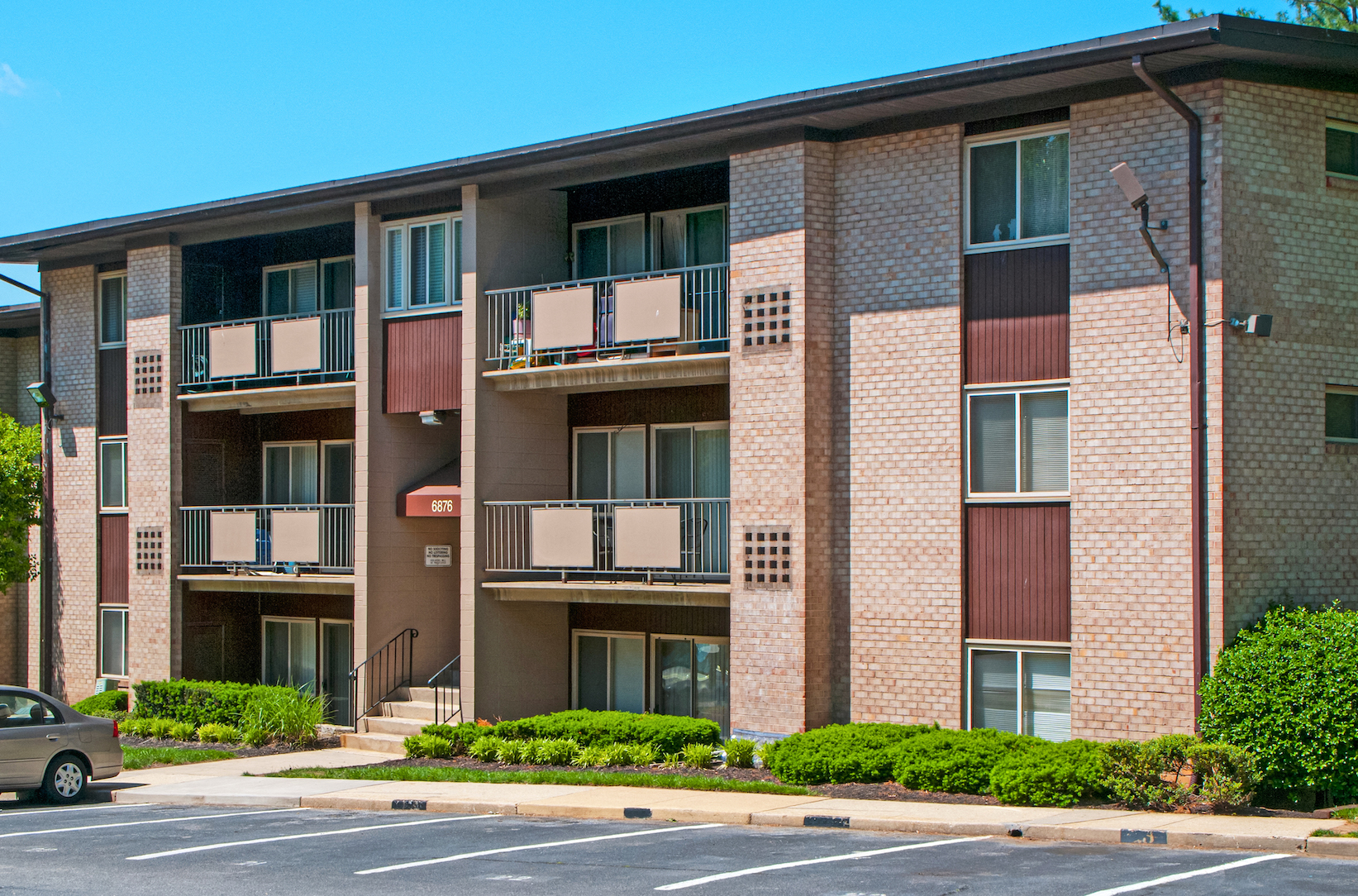 a brick apartment building with balconies and a car parked outside