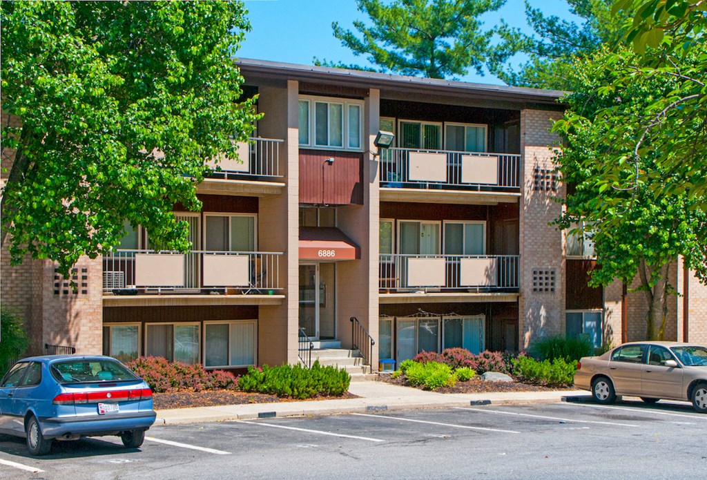 an apartment building with two cars parked in front of it