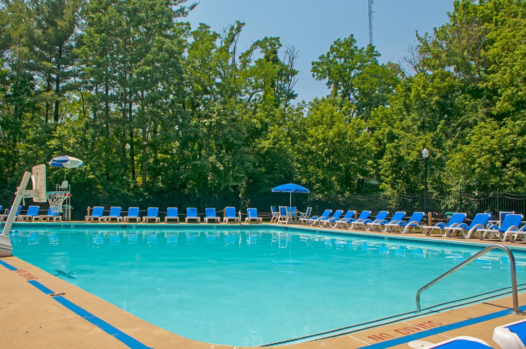 a swimming pool with blue chairs and umbrellas at the resort