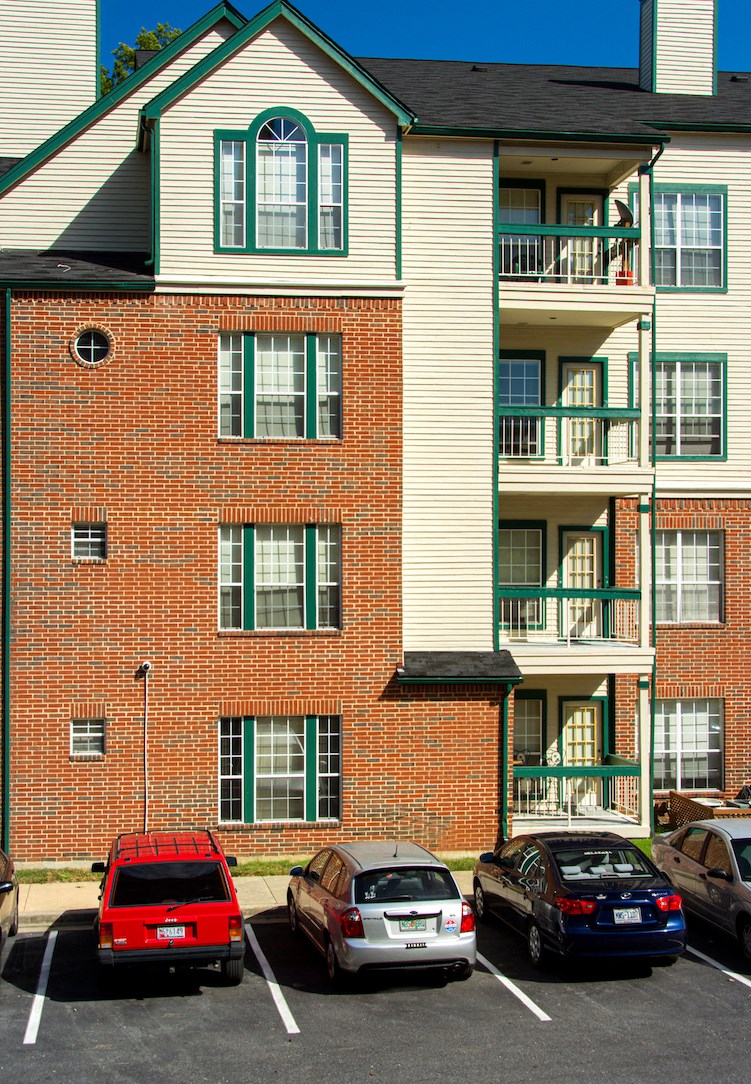 an apartment building with cars parked in a parking lot