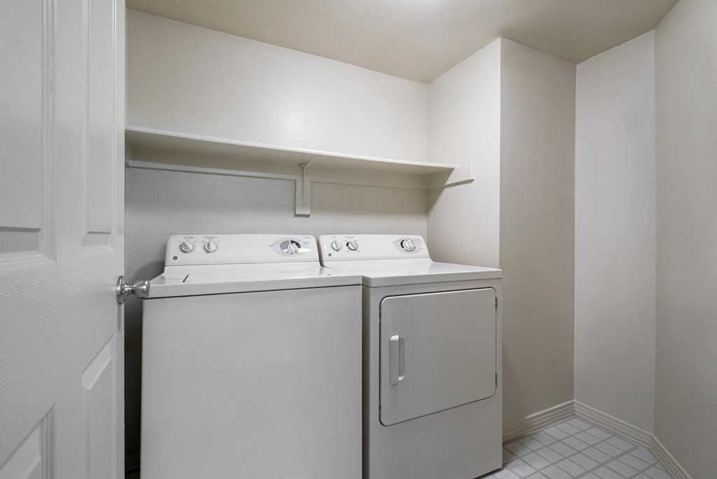 an empty laundry room with a washer and dryer in it