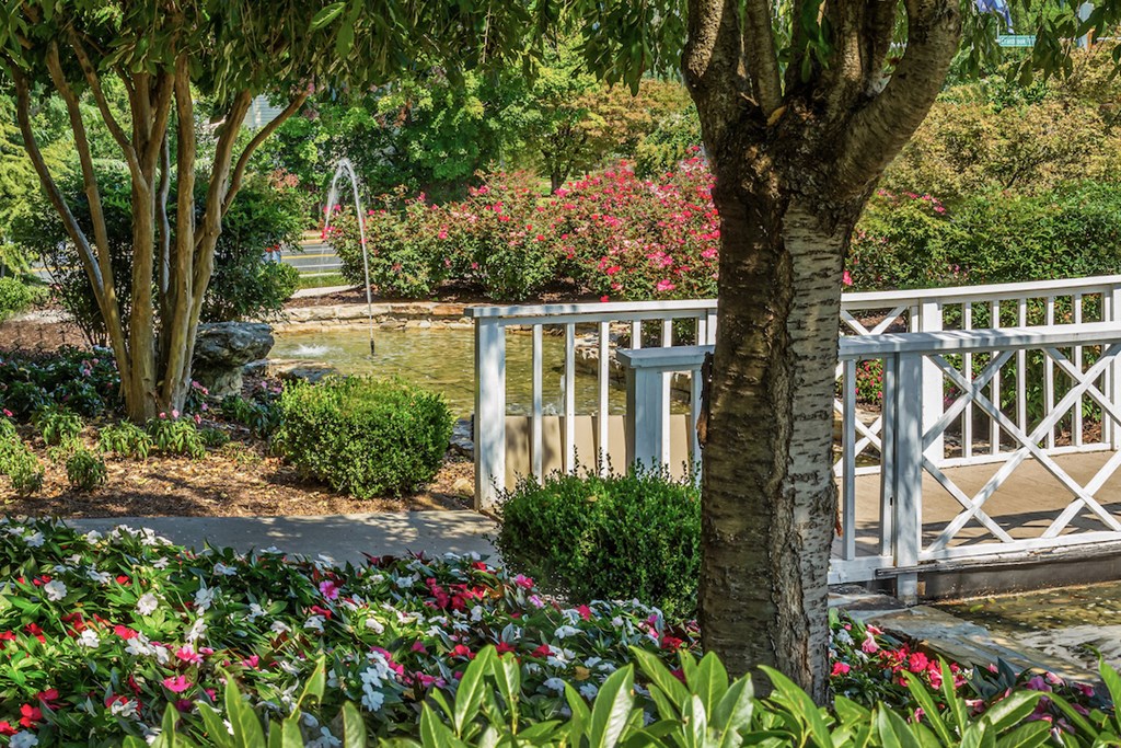 a garden with a bridge and trees and flowers