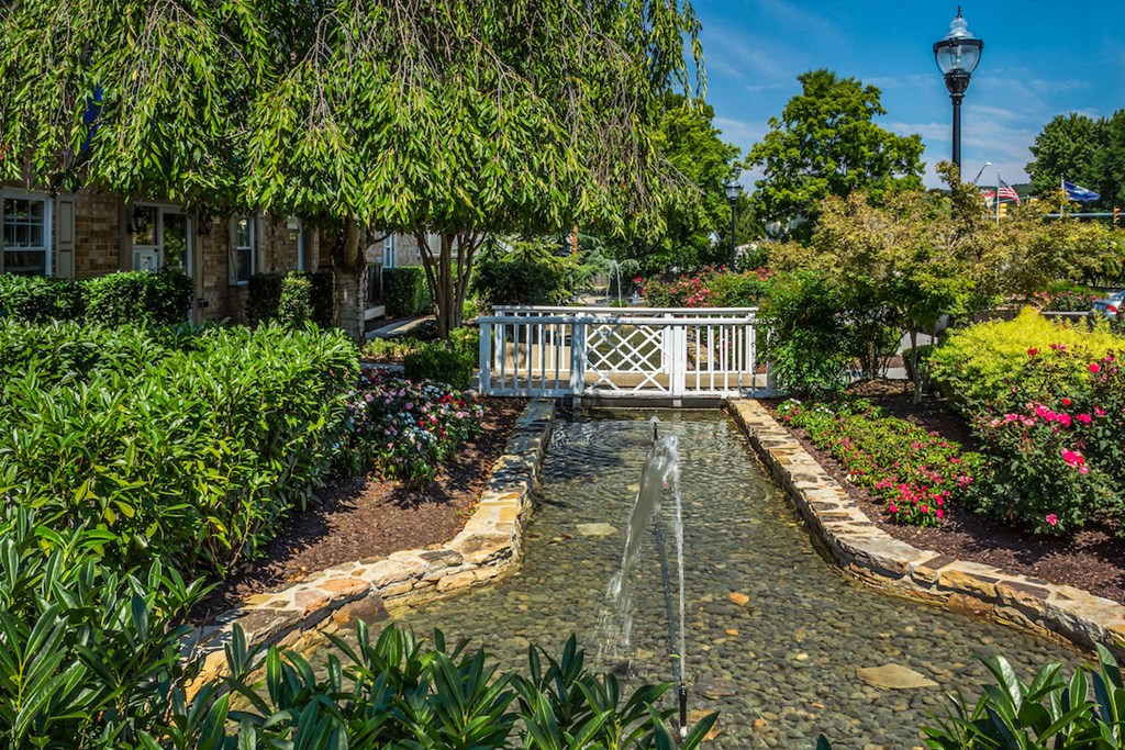 a garden with a fountain and a white bridge