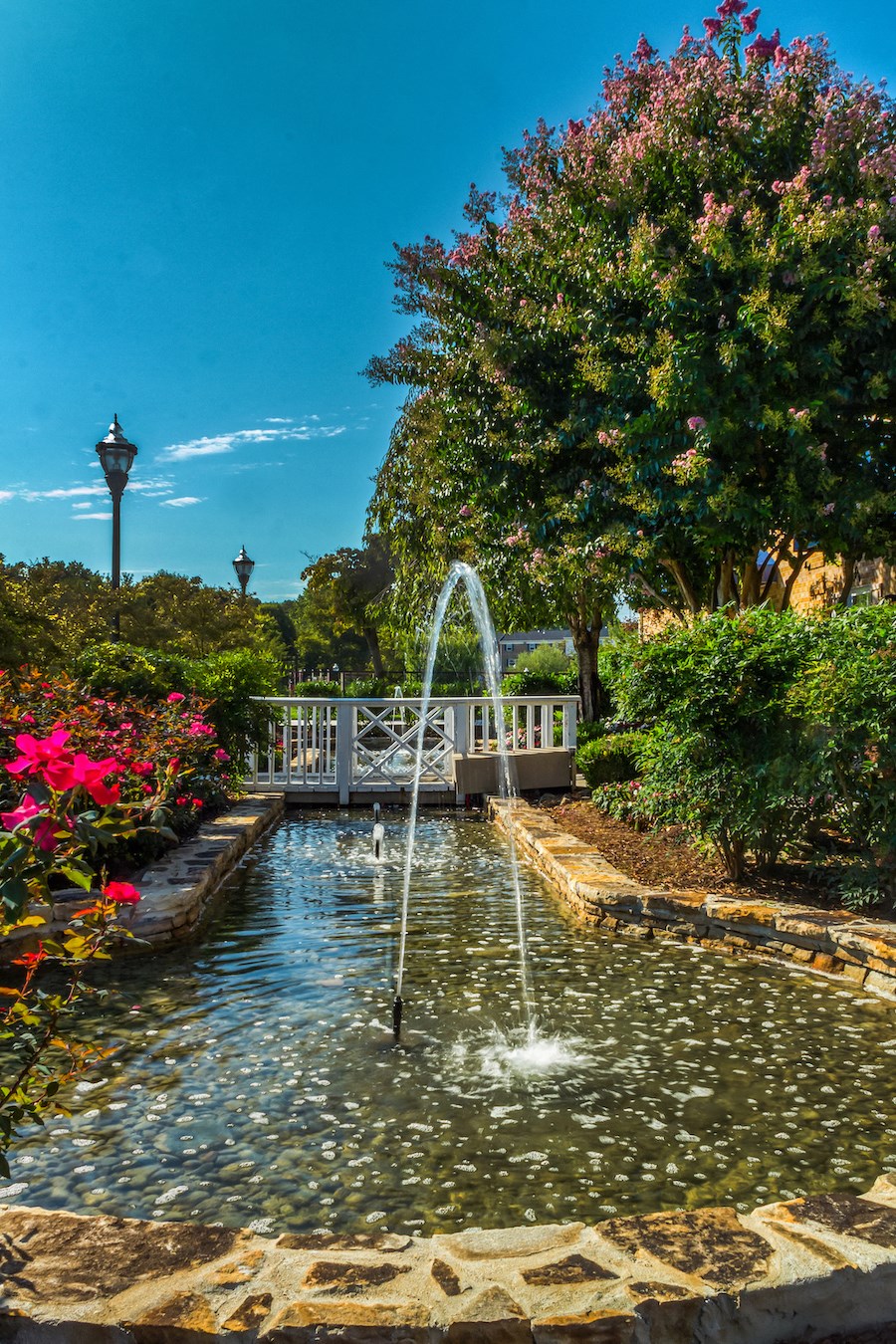 a fountain in the middle of a pond with a bridge