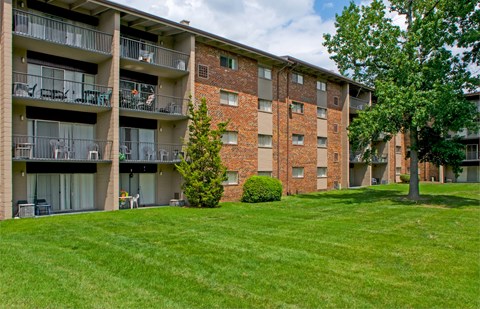 an apartment building with green grass and trees in front of it