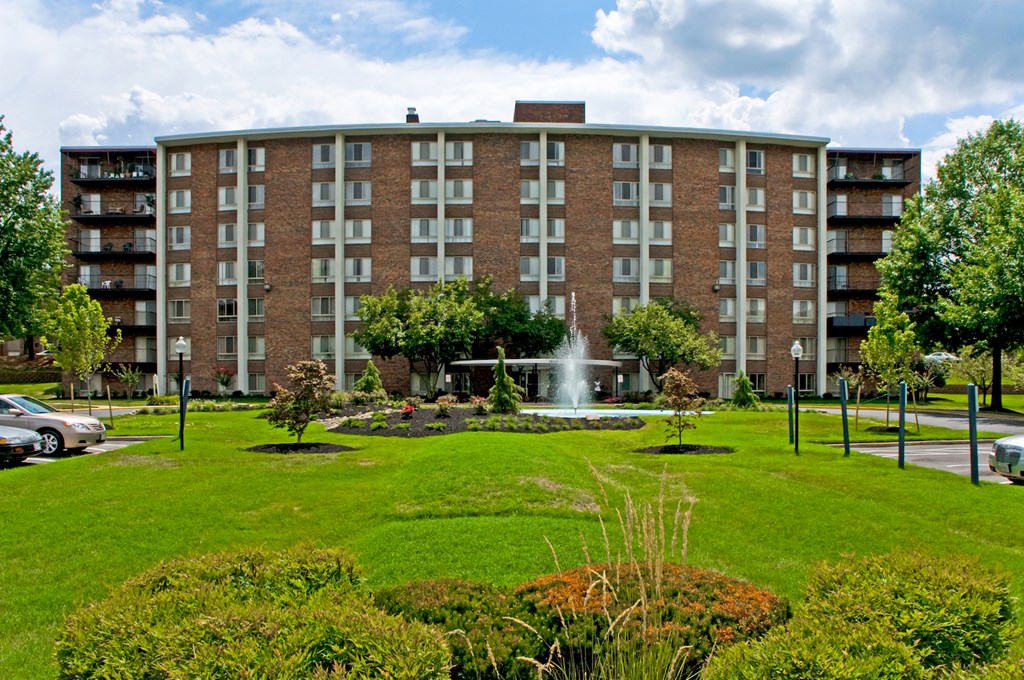 a large brick building with a fountain in a park
