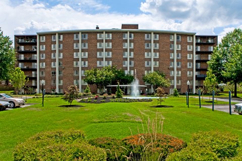 a large brick building with a fountain in a park