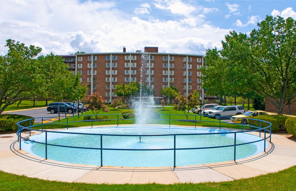 a fountain in the middle of a pool in front of a building