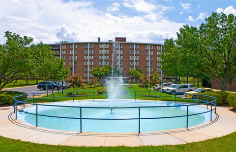 a fountain in the middle of a pool in front of a building