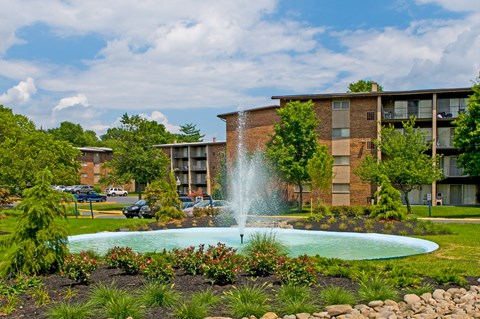 a fountain in a garden in front of an apartment building