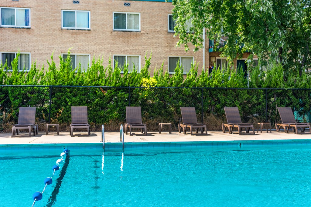 a swimming pool with chairs and a building in the background
