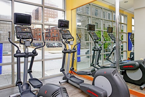 a gym with cardio machines and a view of a city street