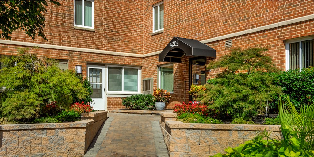 a walkway in front of a brick building with plants and flowers