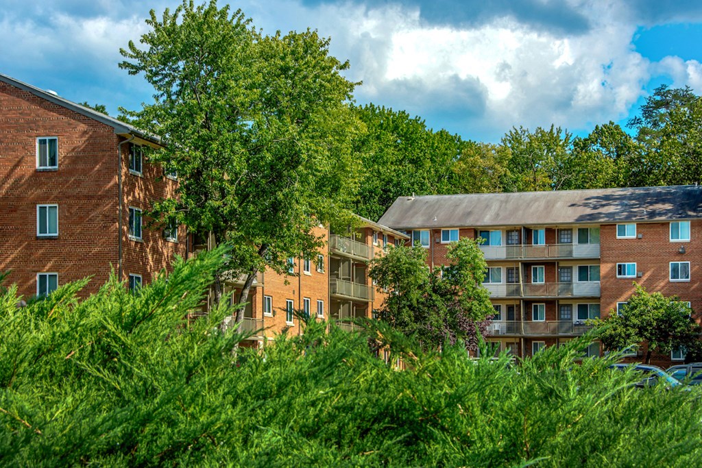 a view of an apartment building with trees and bushes