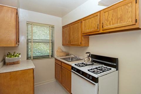 a kitchen with white appliances and wooden cabinets and a window