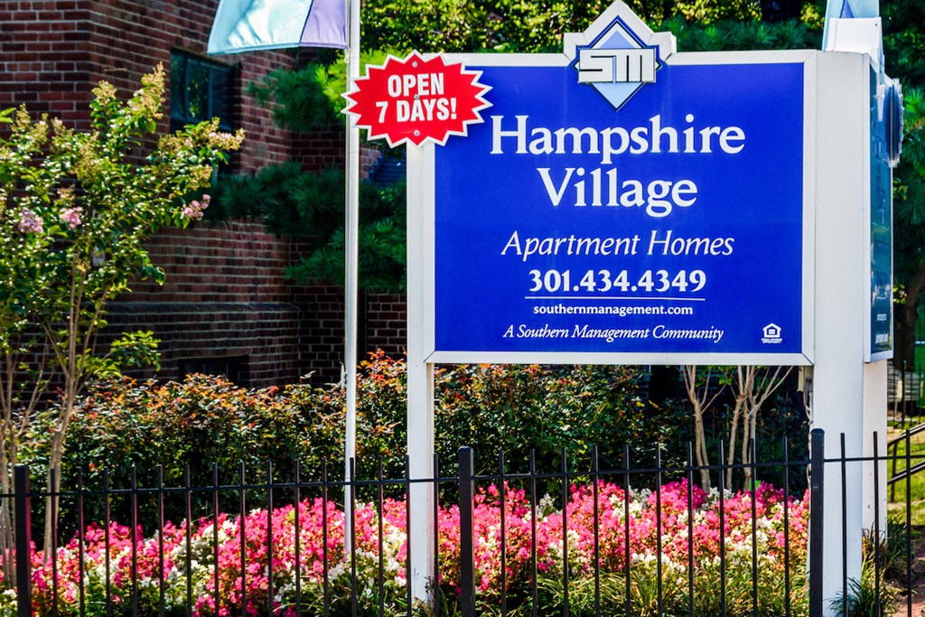 a sign apartments in front of flowers